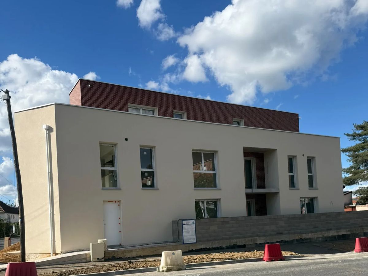Petit collectif de neuf logements en cours d'achèvement à Bihorel, façade enduite et attique en brique